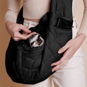 A black quilted puffer material crossbody pet carrier bag photographed with a small black and white dog in it and a zipper that fits an iPhone.