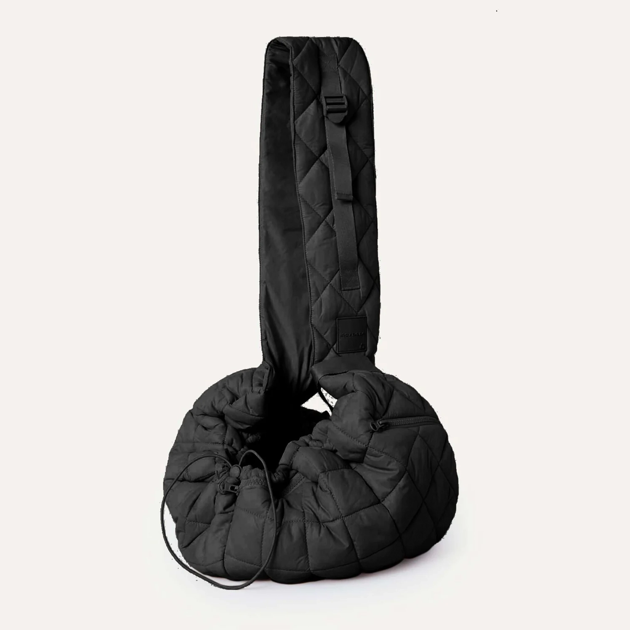 A black quilted puffer material crossbody pet carrier bag with a thick strap, a side zipper and a drawstring adjuster.