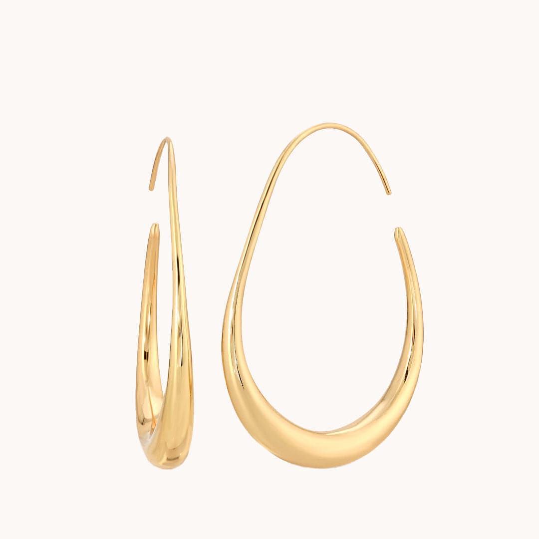 A gold oval shaped hoop earring with a thicker center piece compared to the sides of the hoops.