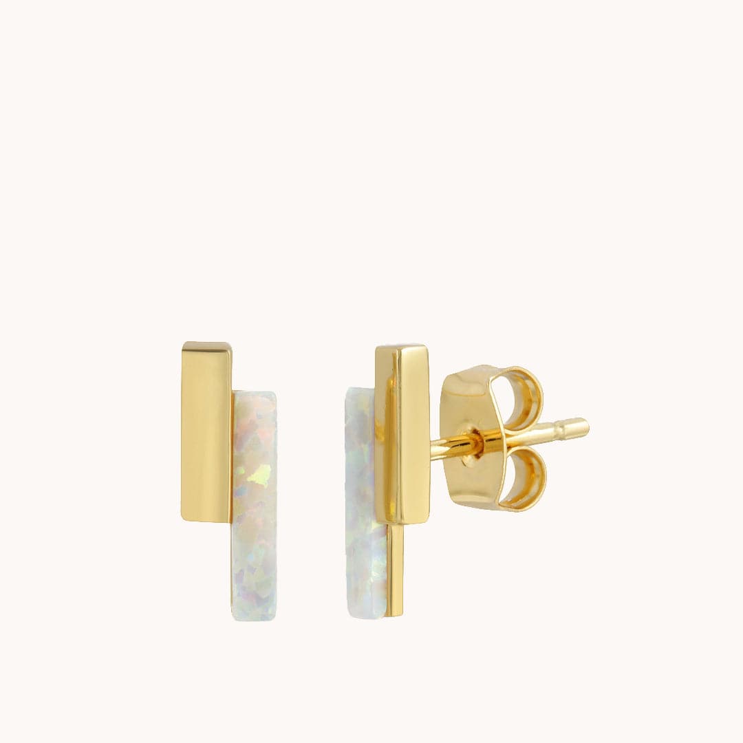On a white background is a pair of stud earring with two vertical bars staggered against one another. One is opal and the other is gold plated.