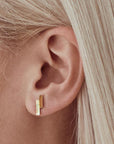 On a model's ear is a stud earring with two vertical bars staggered against one another. One is opal and the other is gold plated. 