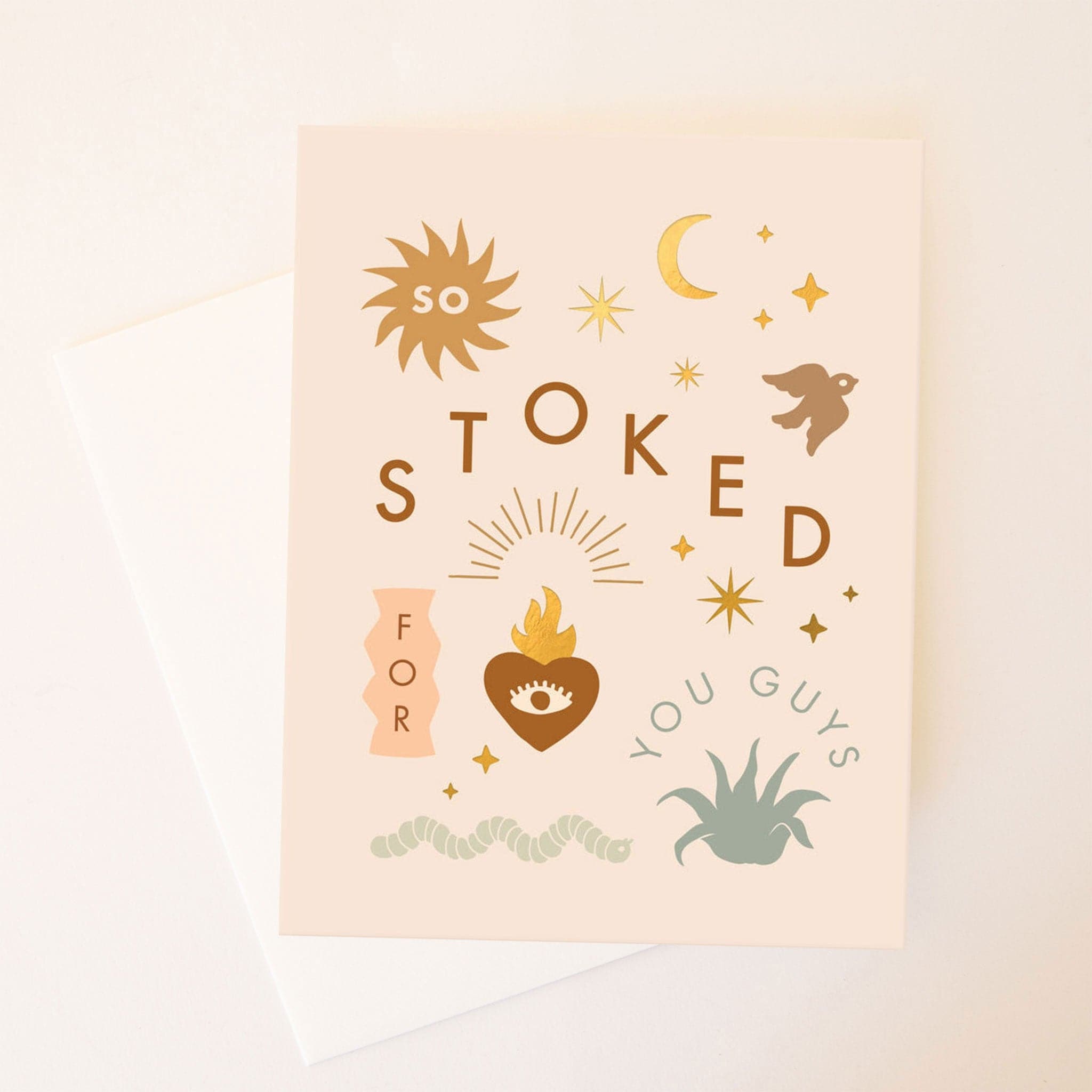 A super light blush pink card with a bunch of individual graphics on the front including a sparrow, a sun, moon and stars, an aloe plant, and a snake along with words spiratcally placed next to or inside of the graphic and reads, &quot;So Stoked For You Guys&quot;. Also included is a white envelope.