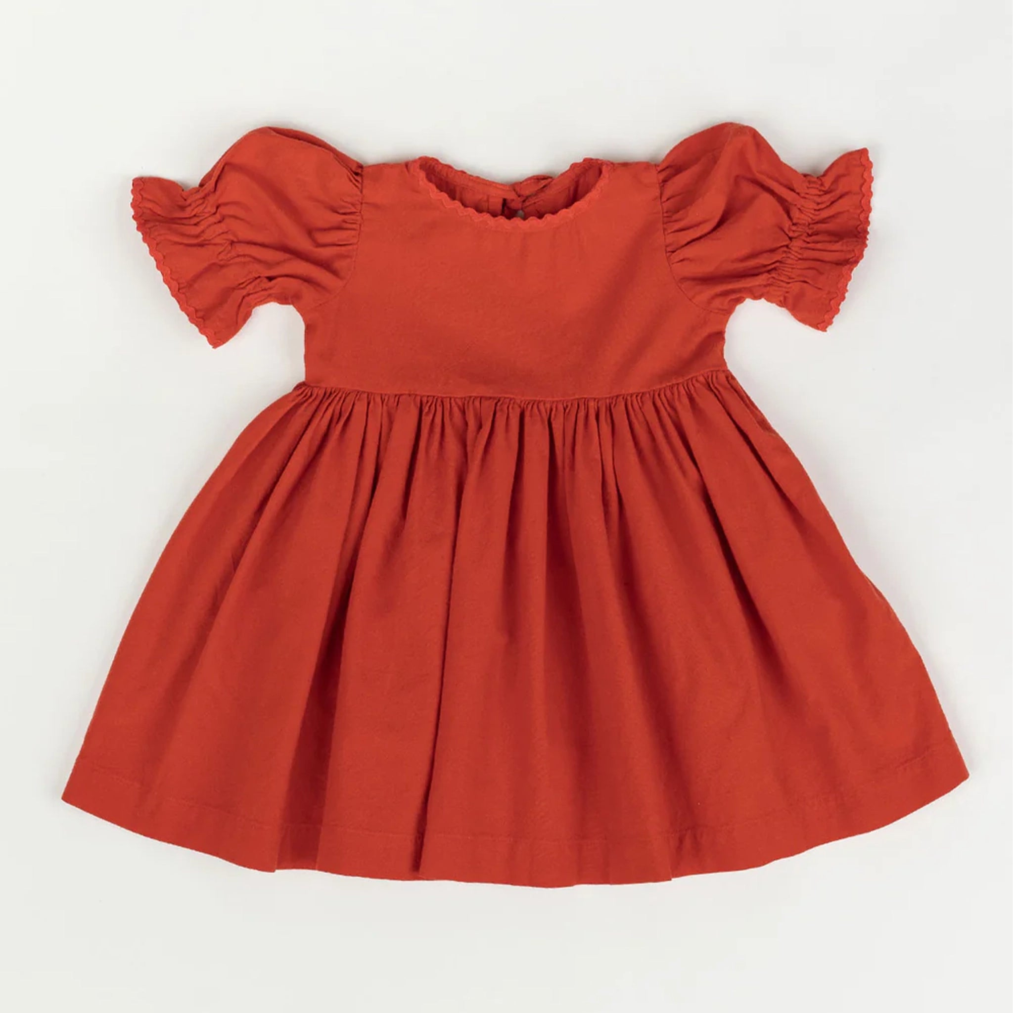 The red baby doll dress with puffy sleeves laying flat on a white background. 