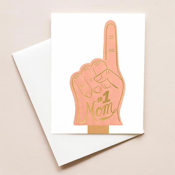 A natural white card with pink sports foam finger with "#1 Mom" in gold foil. Card is blank on the inside. Comes with natural white envelope.