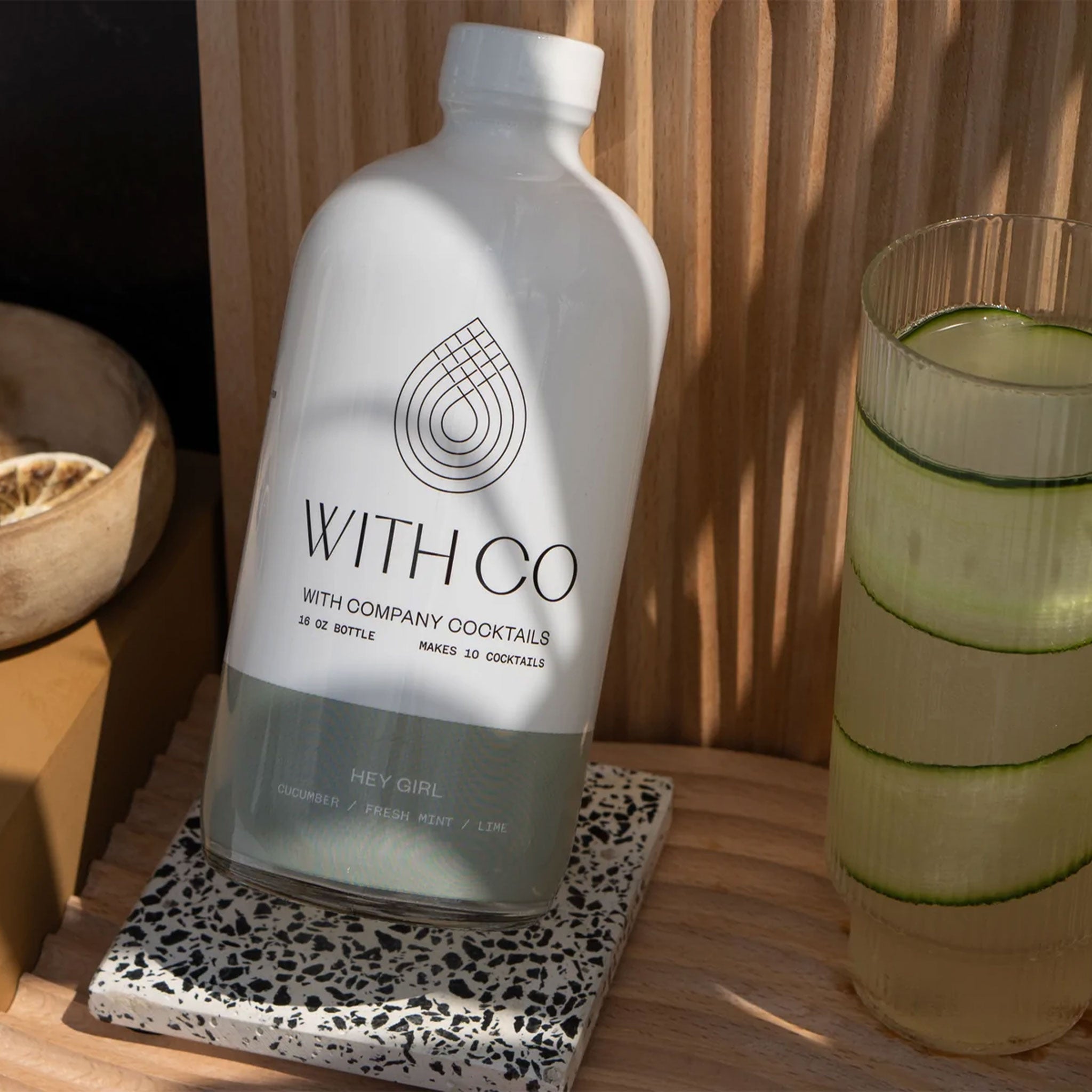 A white container with a sage green bottom half along with the brand &quot;With Co&quot; written in black text along with the name of the cocktail mix &quot;Hey Girl&quot; in white text on the green background.