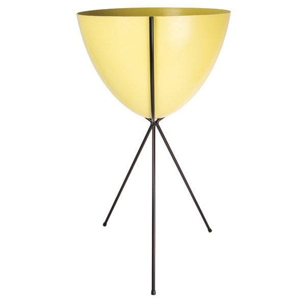 In front of a white background is a yellow colored bullet planter. The planter has a wide top and narrows at the bottom. The planter is held up by a black metal stand. The stand has three black metal legs.