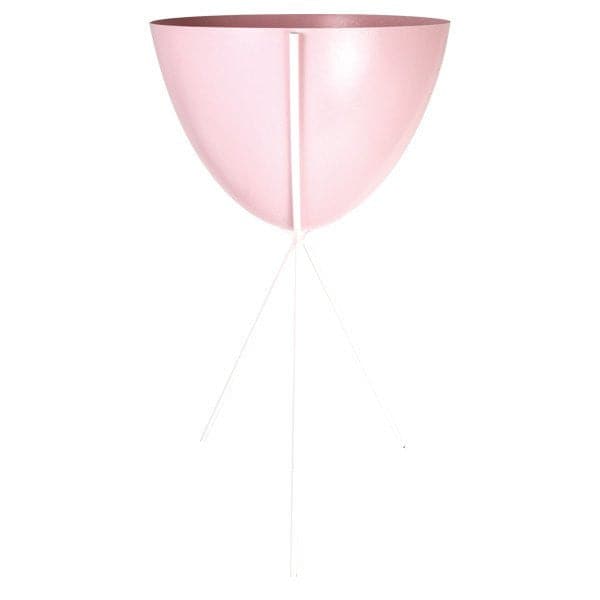 In front of a white background is a pink colored bullet planter. The planter has a wide top and narrows at the bottom. The planter is held up by a white metal stand. The stand has three white metal legs.
