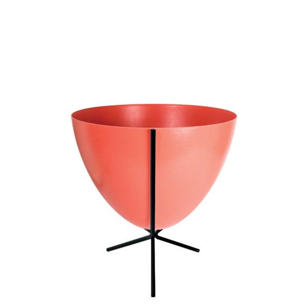 In front of white background is a red planter in a short black metal stand. The bullet planter is wide at the top and narrow at the bottom. The metal stand has three legs.