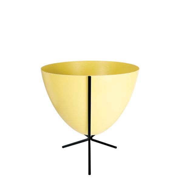 In front of white background is a yellow planter in a short black metal stand. The bullet planter is wide at the top and narrow at the bottom. The metal stand has three legs. 