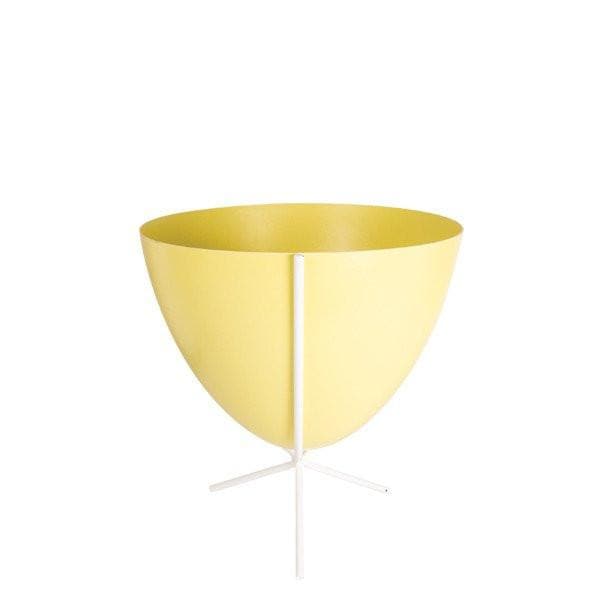 In front of white background is a yellow planter in a short white metal stand. The bullet planter is wide at the top and narrow at the bottom. The metal stand has three legs. 