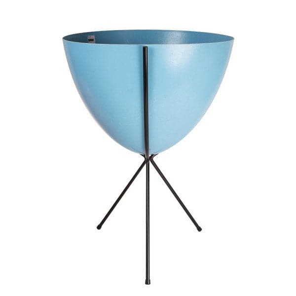 In front of white background is a bright blue planter in a black metal stand. The bullet planter is wide at the top and narrow at the bottom. The metal stand has three legs. 