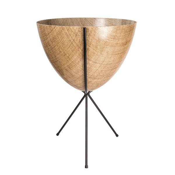 In front of white background is a wood colored planter in a black metal stand. The bullet planter is wide at the top and narrow at the bottom. The metal stand has three legs. 