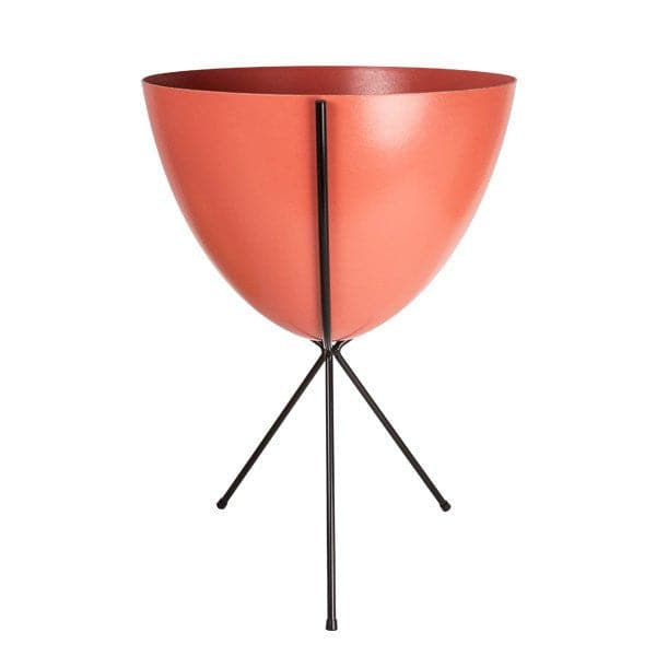 In front of white background is a red planter in a black metal stand. The bullet planter is wide at the top and narrow at the bottom. The metal stand has three legs. 