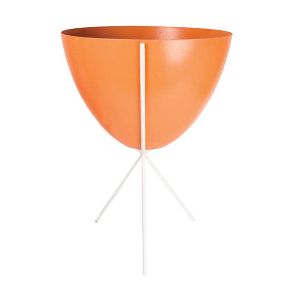 In front of white background is an orange planter in a white metal stand. The bullet planter is wide at the top and narrow at the bottom. The metal stand has three legs. 