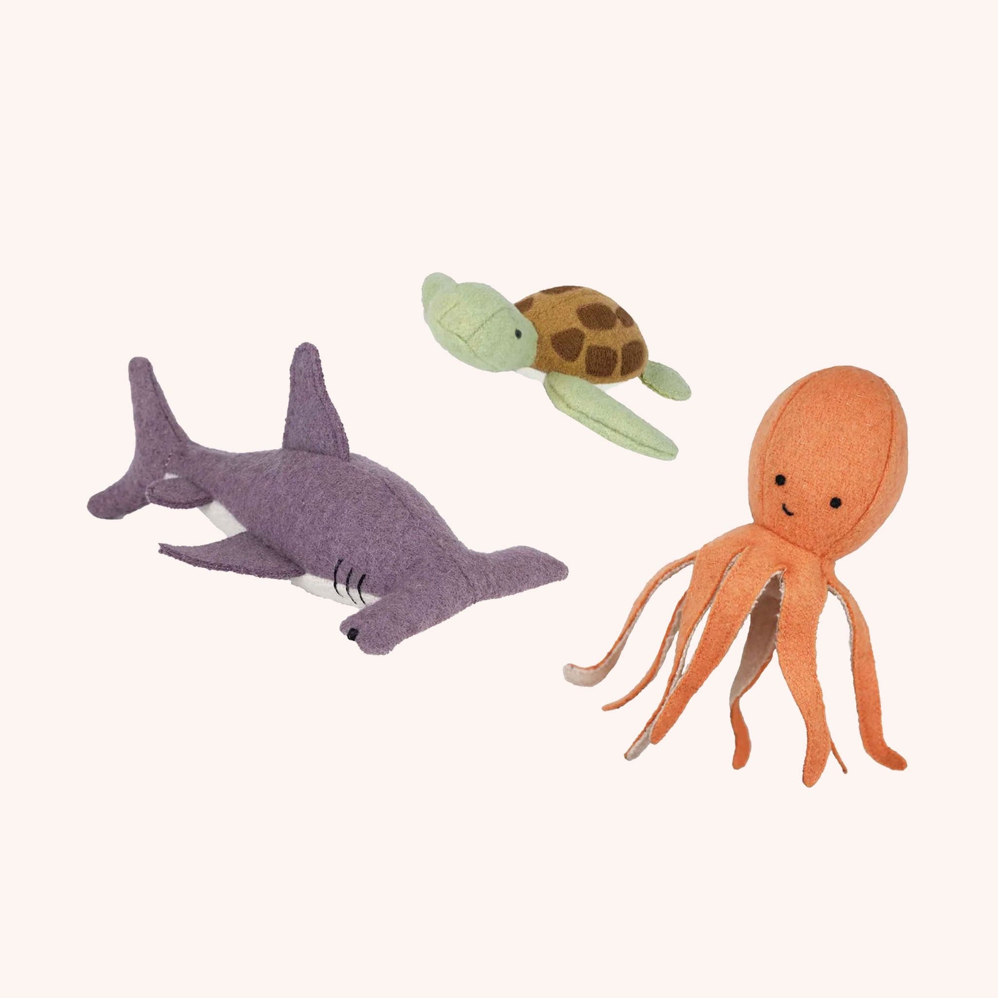 three marine inspired stuffed toys, that includes an orangey red octopus, a great hammerhead shark and a green and brown sea turtle.