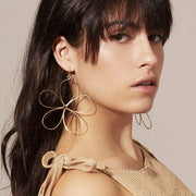 A woman modeling the Azuma Earrings, with large bent gold wire gold petals.