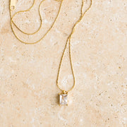 A thin gold chain necklace with a singular CZ emerald cut stone.