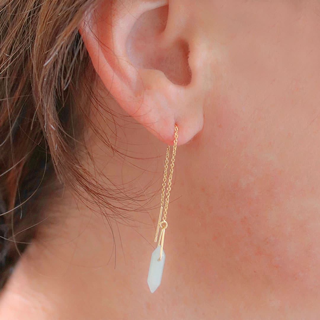 Single gold plated hanging, chain earring modeled on ear. Earring has a soft blue amazonite stone positioned between a gold loop.