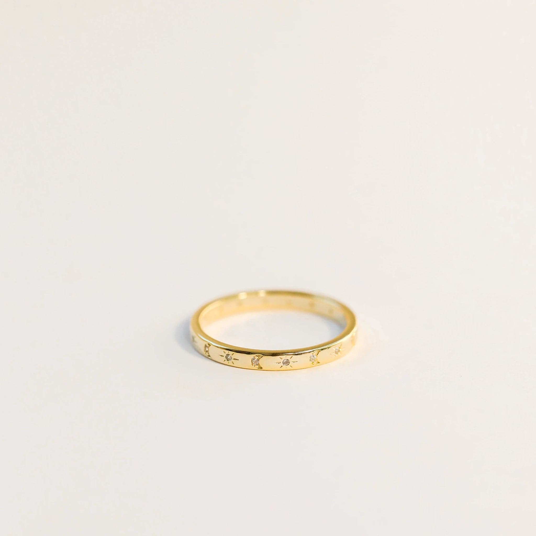 Delicate gold ring with etched suns and moons circling the band. Each sun and moon has a CZ gem in the center.