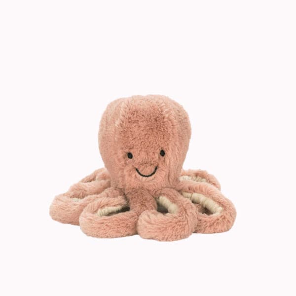 A pink octopus stuffed animal with a smiling face, photographed on a cream background.