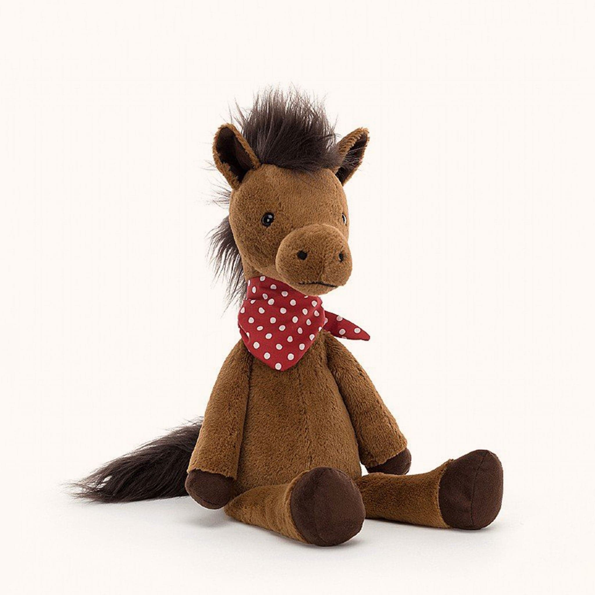 Soft stuffed animal in the shape of a brown horse with fluffy dark brown mane and tail, and wearing a red and white spotted bandana around its neck.