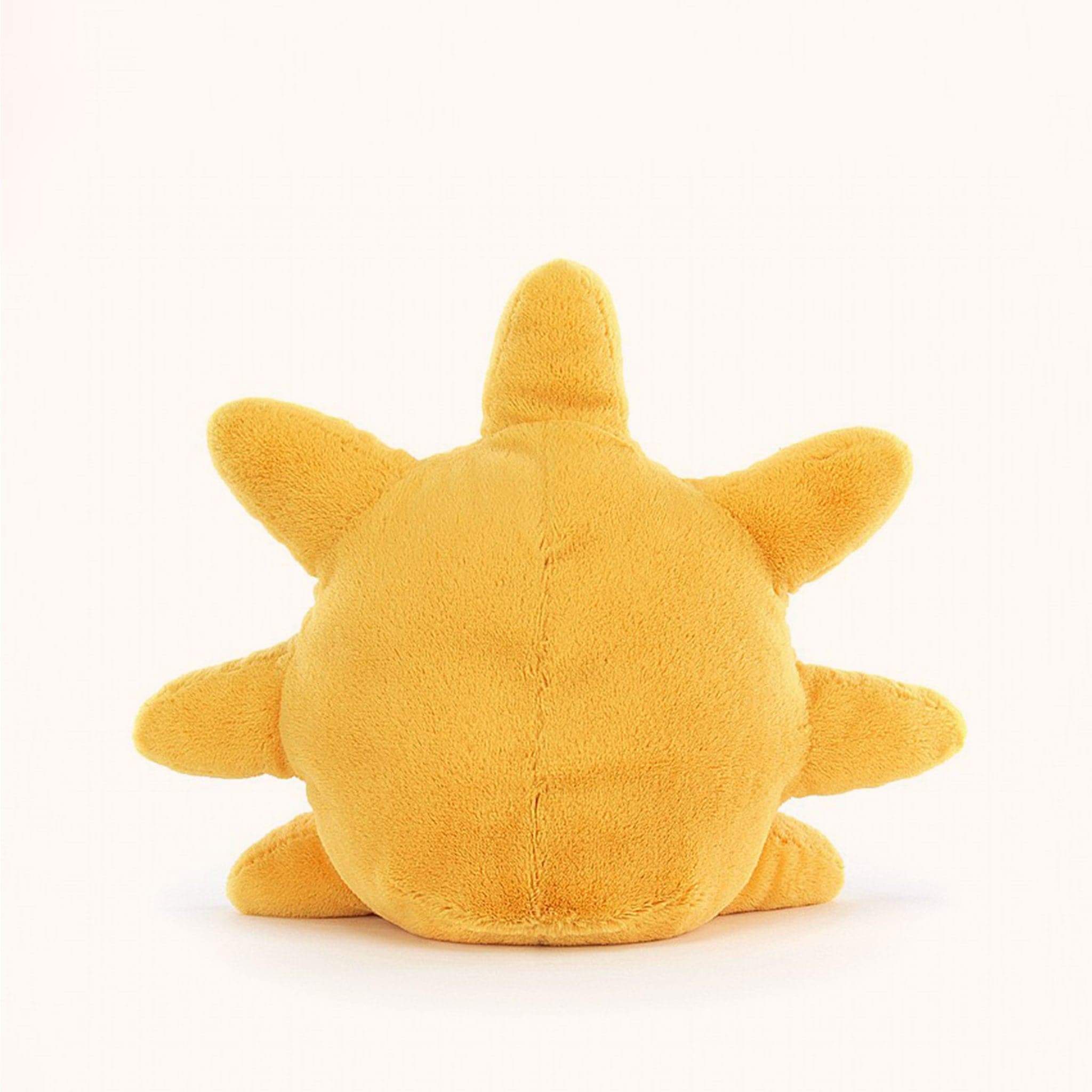 Soft stuffed animal in the shape of a yellow sun, with a smiley face and floppy brown legs.