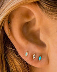 On a models ear is oval shaped stud earrings with an opal in the center. 