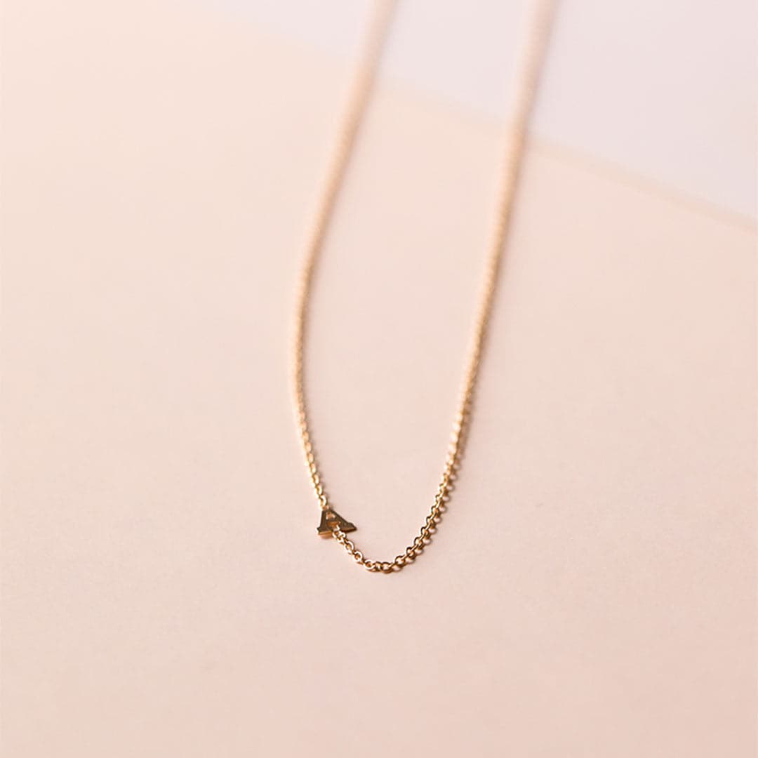 A dainty gold chain necklace with an "A" on the chain.