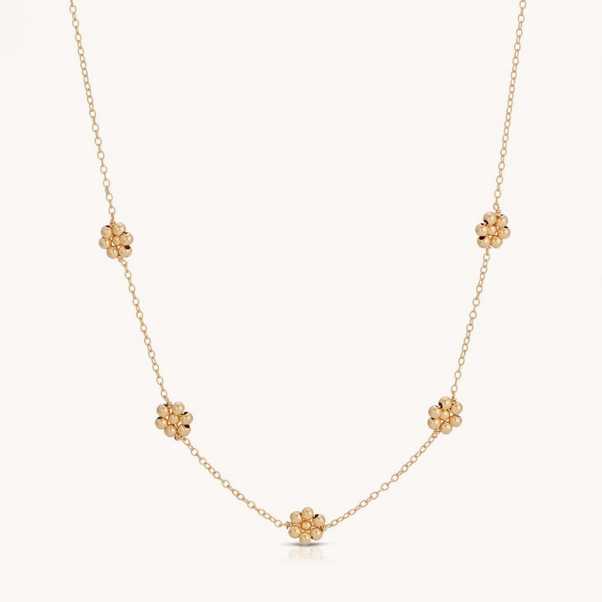 Gold chain necklace with five spaced out beaded flower details.