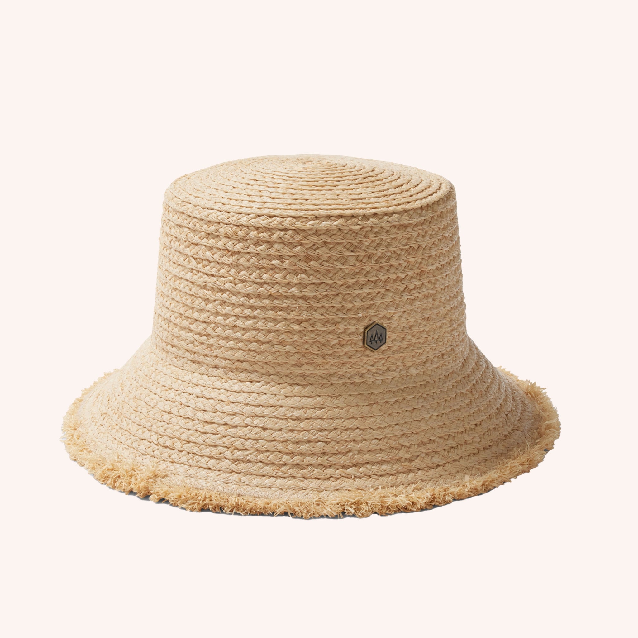 A woven bucket hat in a light straw color with a frayed edge detail along the edge of the brim and a tiny hemlock hat metal emblem in the center.