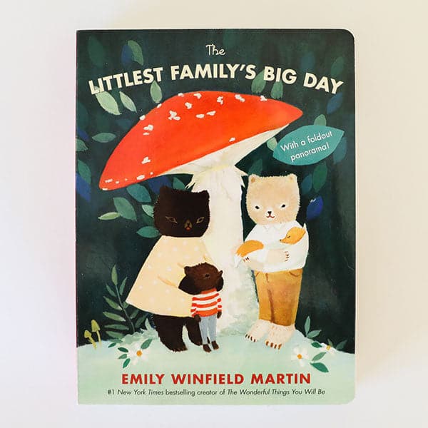 This book cover features a family of miniature bears and fox pup. The family stands below a classic red and polk-a-dot mushroom. The title reads &#39;The Littlest Family&#39;s Big Day&#39; in light lettering above. The background is filled with green and blue toned leaves and details.  