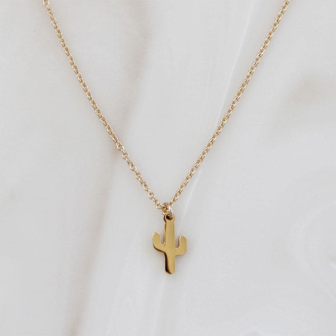 A dainty gold chain necklace with a small cactus pendant.
