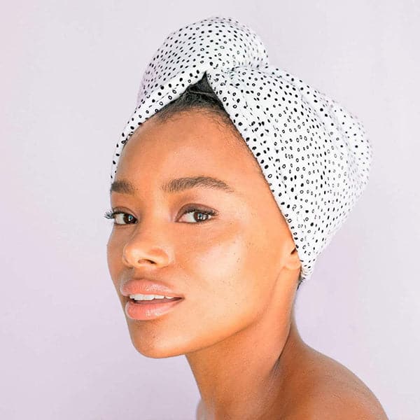  A white microfiber hair towel with tiny black polka dot design all over being modeled wrapping up wet hair.
