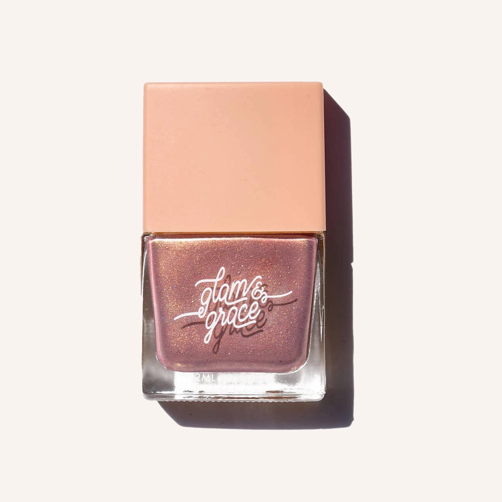 A shimmery pink nail polish in a glass bottle with a square peachy lid.
