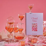 A lavender colored puzzle box that reads, "Cloud Nine" with a photo of what the puzzle looks like. The completed puzzle is a photo of an assortment of drinking glasses filled with a pink drink.