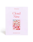 A lavender colored puzzle box that reads, "Cloud Nine" with a photo of what the puzzle looks like. The completed puzzle is a photo of an assortment of drinking glasses filled with a pink drink.