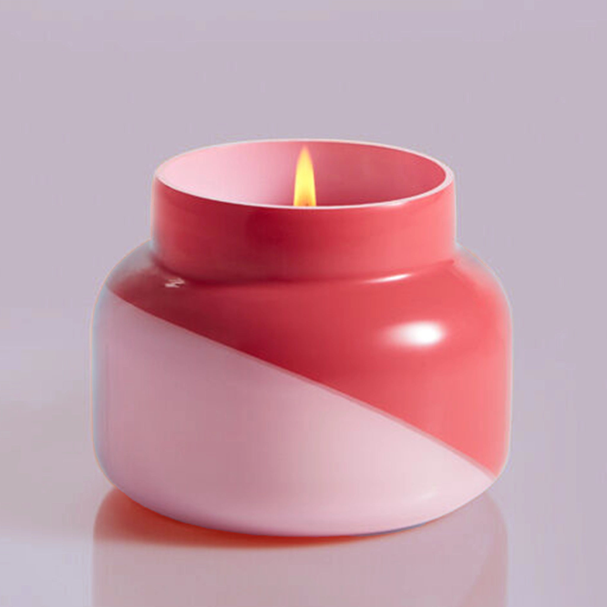 A glass candle jar with a two toned design featuring a light pink and a darker pink that is split diagonally.