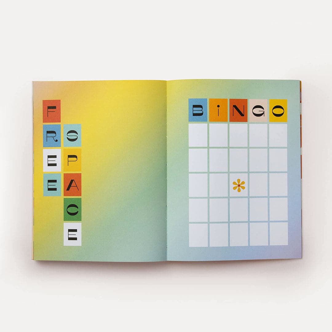 Journal is open and turned to two pages filled with a colorful rainbow ombre background. One reads &#39;Free Space&#39; in abstract, capital lettering with each letter placed in its own colorful box. The other page reads &#39;Bingo&#39; above a bingo board with a marked &#39;Free Space&#39; tile. 