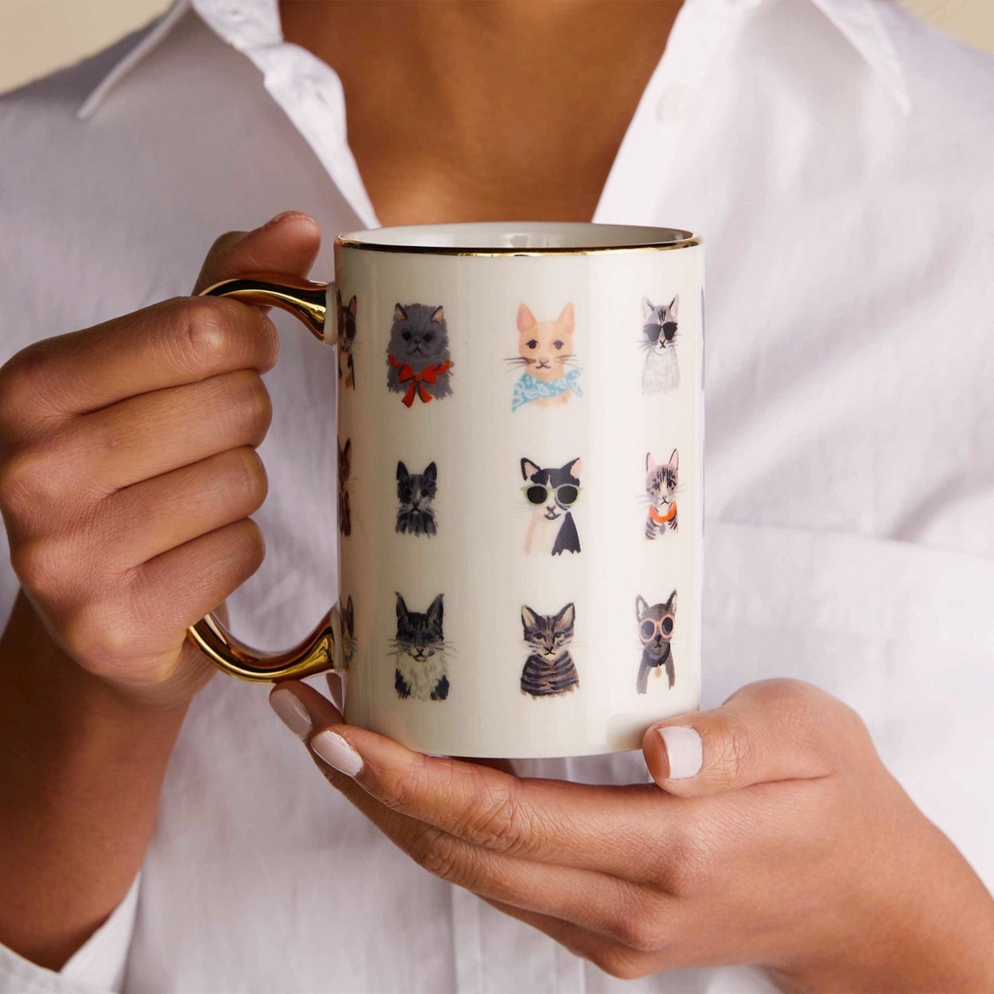 A luxurious porcelain mug featuring rows of different illustrated cats. Some cats are wearing cool sunglasses and patterned bandanas. This mug also has a gold handle and trim.