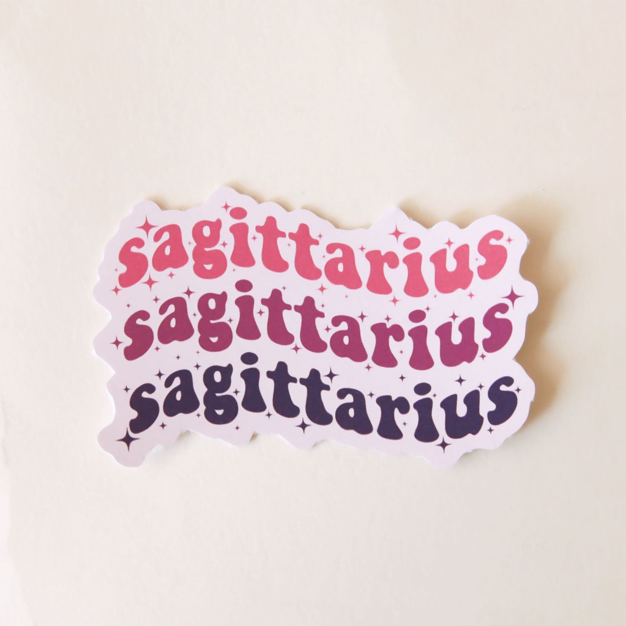 On a white background is a vinyl sticker with the word, &quot;Sagittarius&quot; stacked on top of itself three times. 