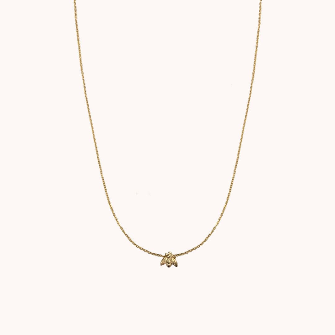 A super dainty gold chain necklace with a tiny bee pendant in the center.