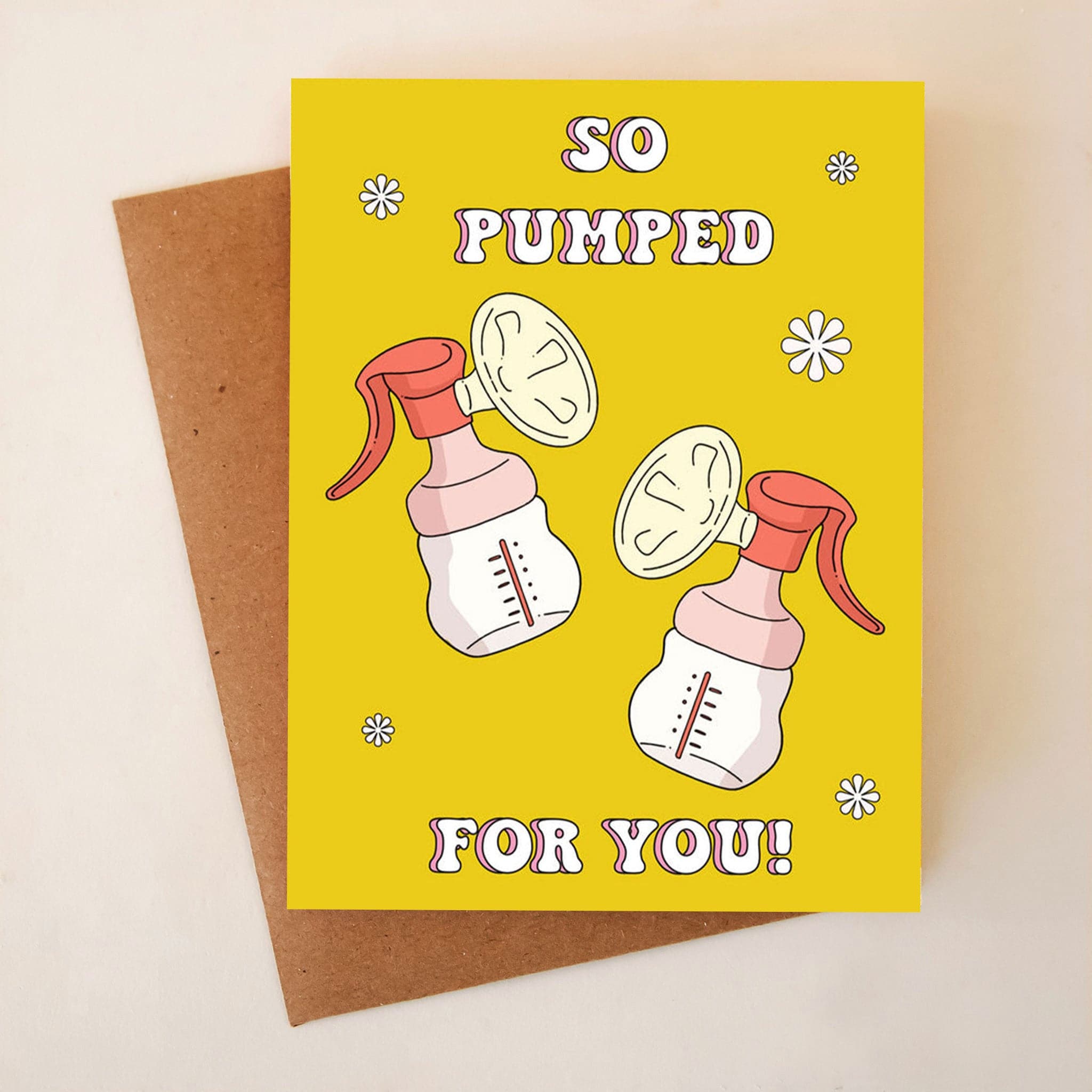 A yellow card with 70&#39;s style white font that reads, &quot;So Pumped For You&quot; along with two breast pumps and sporadic white daisies.