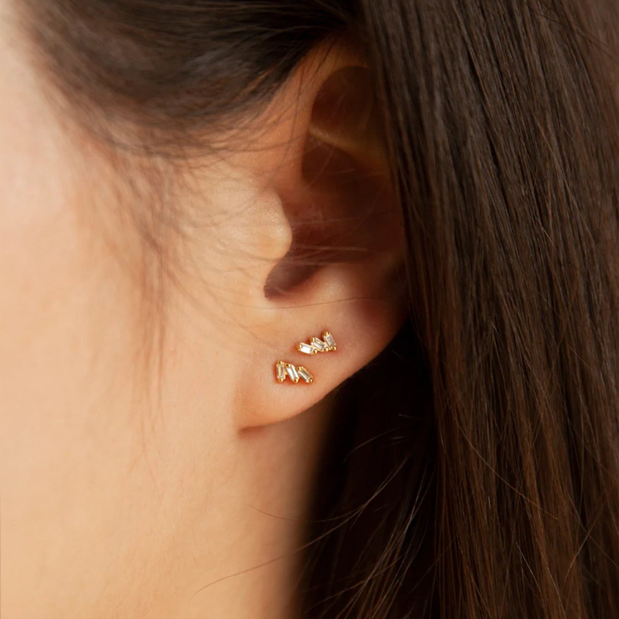 A cubic zirconia stud earring with 3 tiny baguette stones.