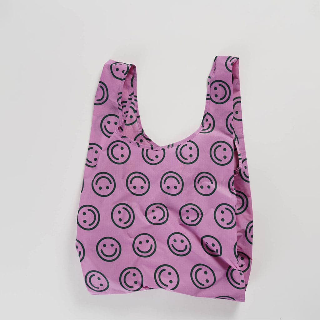 Purple reusable bag with a pattern of forest green smiley faces throughout. 
