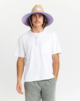 A woven straw sun set with a wide brim, a light purple drawstring and purple detailing underneath the brim of the hat as well as on the center label.