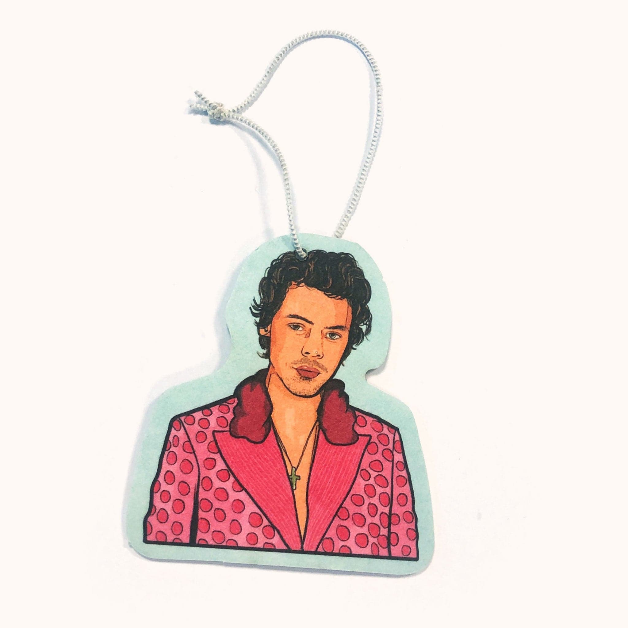 Light aqua air freshener with display the top half of Harry Styles wearing an iconic pink polo dot suit and cross necklace. A white elastic loop is fastened above ready to be hung. 