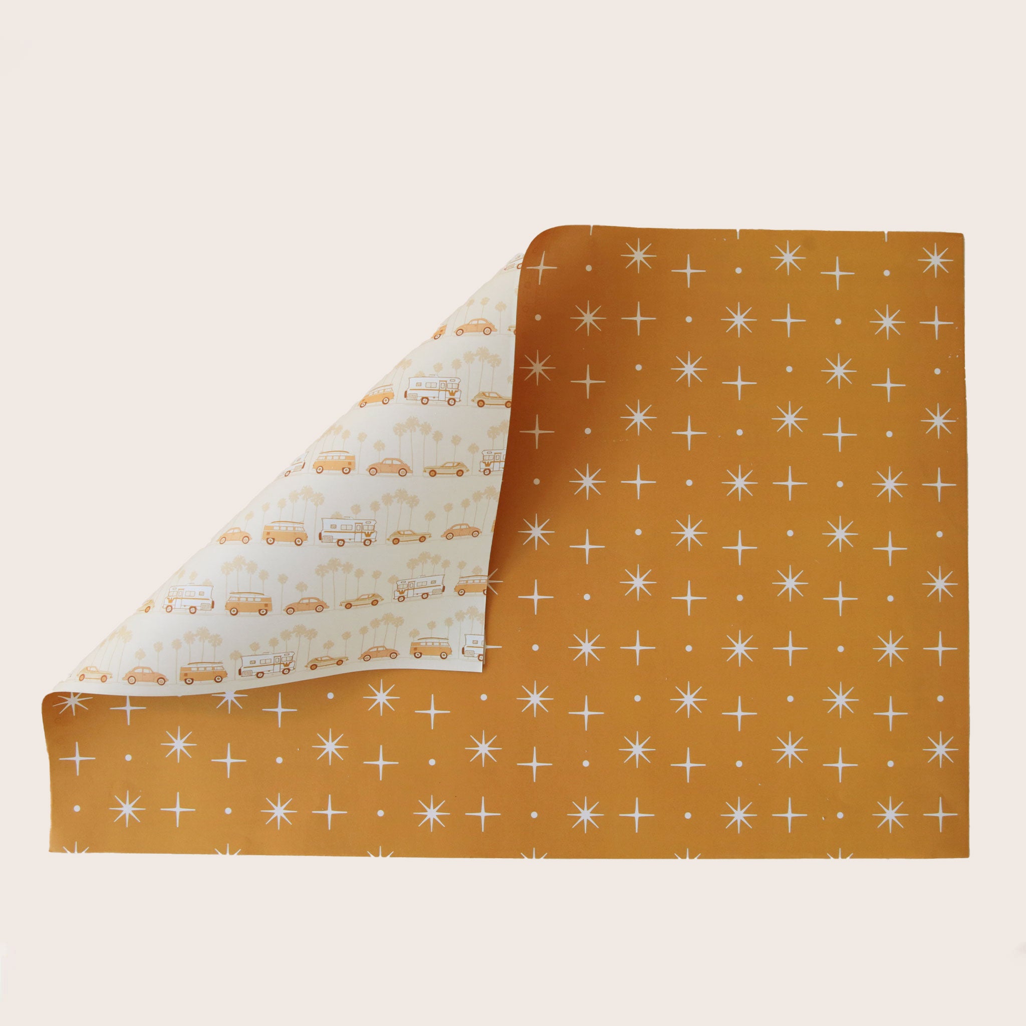 A single sheet of gift wrap featuring a mustard yellow background with a repeating white star design. On the flip side, you have the option of a cream background with groovy vehicles including vintage inspired RV's, and VW bugs and buses.