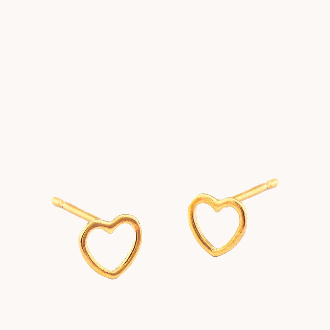 A model wearing dainty gold open heart stud earrings.