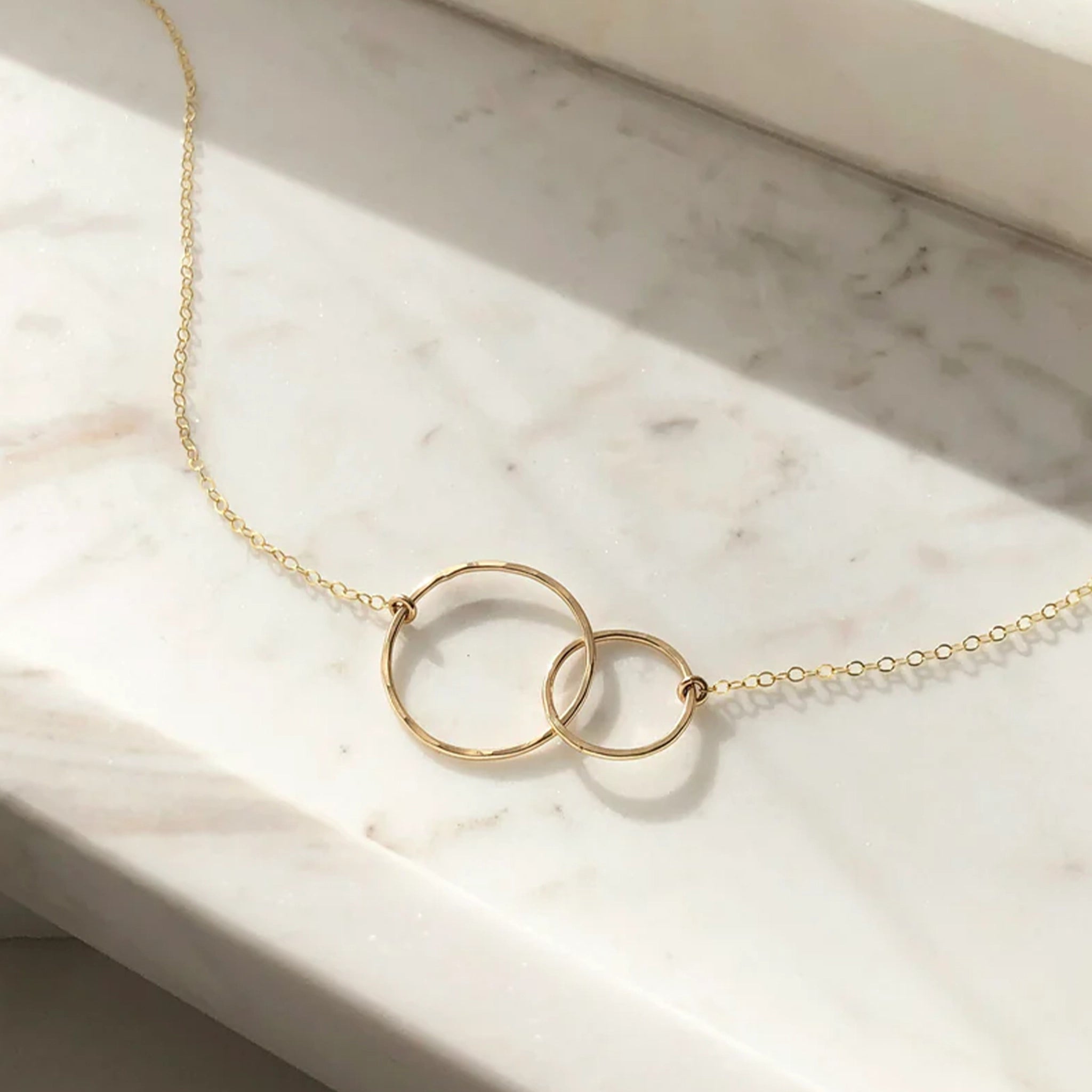 the unity necklace features two gold circles, hand forged and lightly hammered that come together and hang from a beautiful chain.