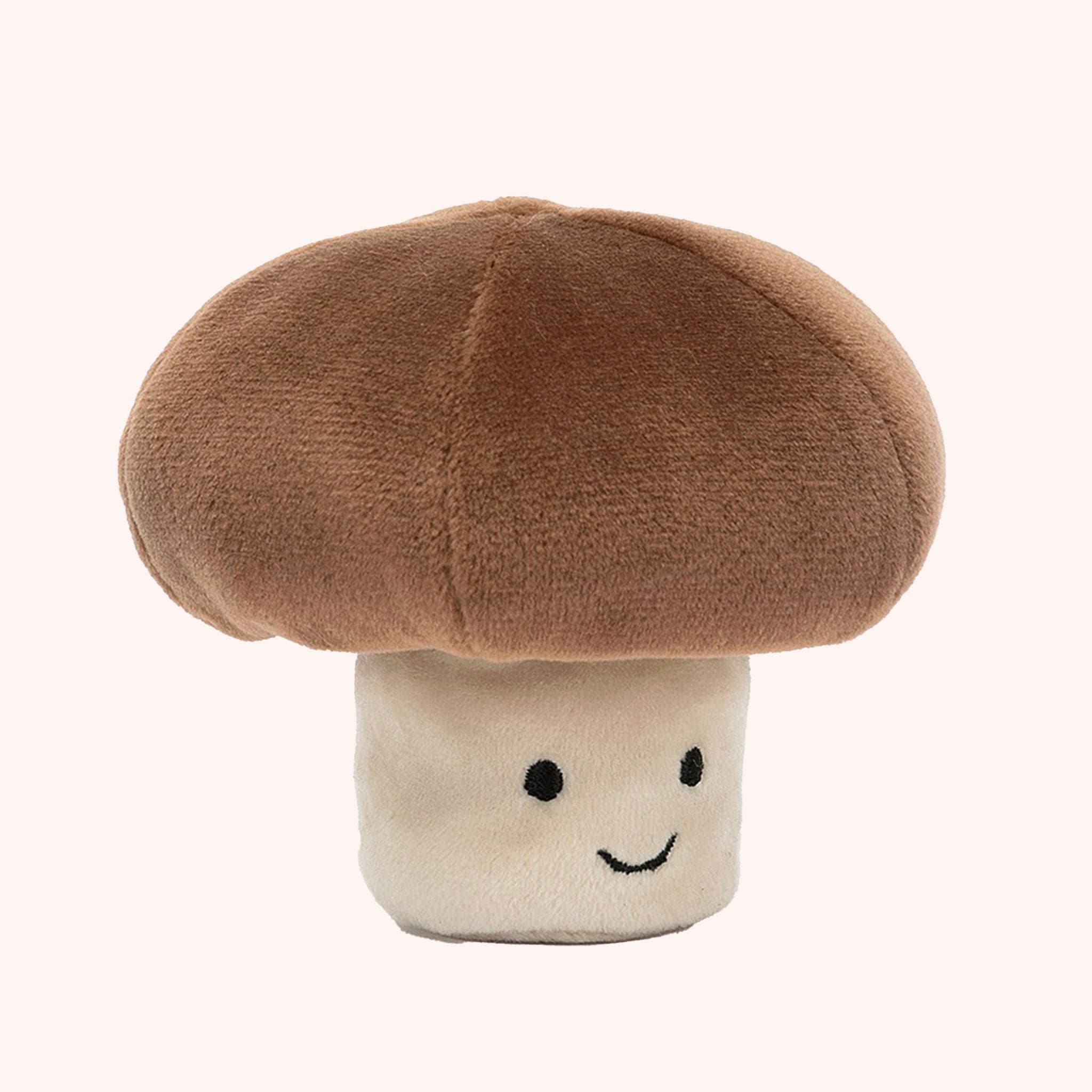 A sweet mushroom stuffed toy with a brown top and a light beige stem along with a smiling face.